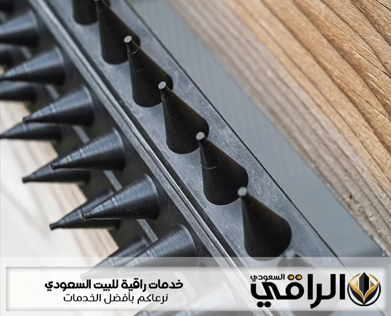 أشواك سوداء مثبتة بمحاذاة سطح خشبي ضمن تجهيزات شركة تركيب طارد حمام بحفر الباطن لمنع وقوف الطيور بها
