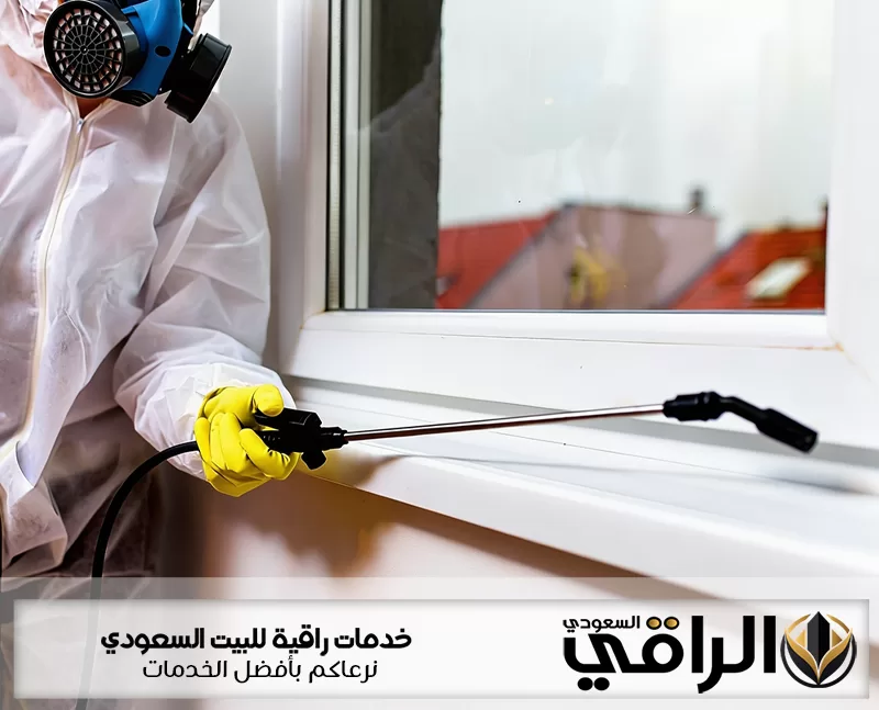 فني شركة مكافحة الحشرات بتيماء يرتدي قناع حماية ويرش المبيد حول حواف نافذة المنزل بأداة رش دقيق جدا